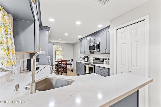 kitchen with stainless steel appliances, sink, backsplash, and gray cabinets