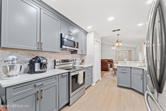 kitchen featuring gray cabinetry, backsplash, lofted ceiling, and appliances with stainless steel finishes