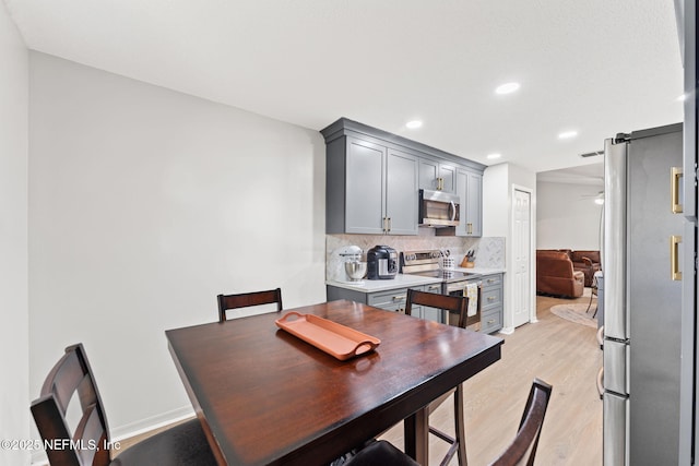 dining space with ceiling fan and light wood-type flooring