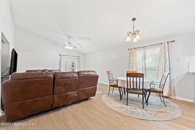 living room with light hardwood / wood-style flooring, ceiling fan with notable chandelier, and vaulted ceiling