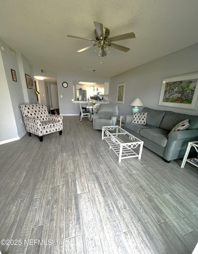 4250 A1A S Unit L16, Saint Augustine, FL 32080 - living room featuring visible vents, wood finished floors, baseboards, a textured ceiling, and ceiling fan with notable chandelier
