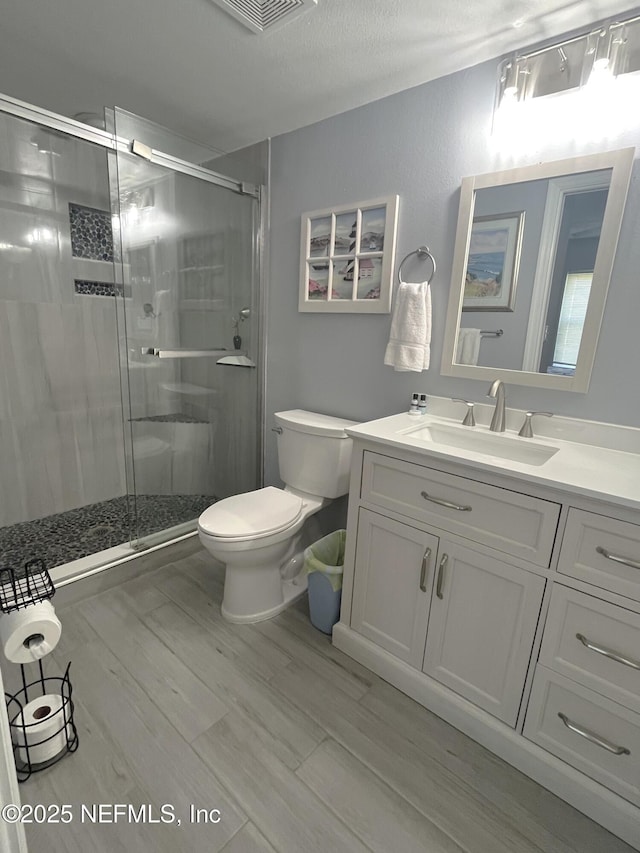 4250 A1A S Unit L16, Saint Augustine, FL 32080 - full bathroom featuring vanity, toilet, a shower stall, wood finished floors, and visible vents