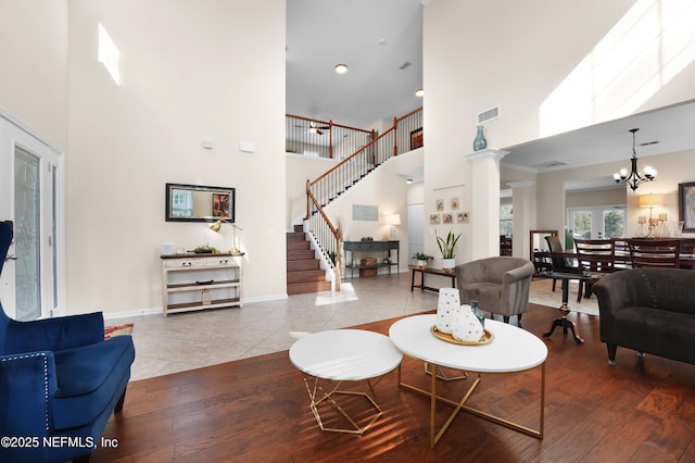 living room with a high ceiling, an inviting chandelier, and light wood-type flooring