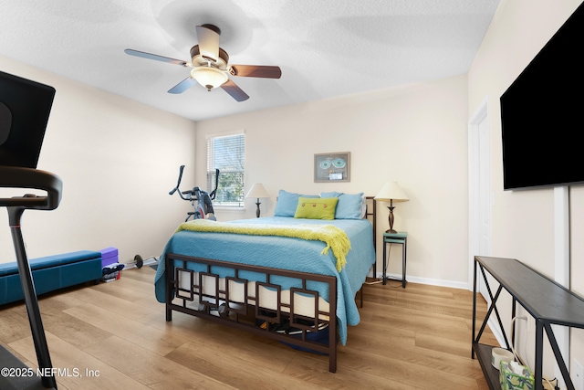 bedroom with ceiling fan, a textured ceiling, and light wood-type flooring