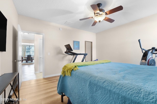 bedroom featuring ceiling fan, a textured ceiling, and light wood-type flooring