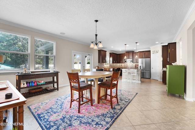 tiled dining area with french doors, ornamental molding, and a textured ceiling