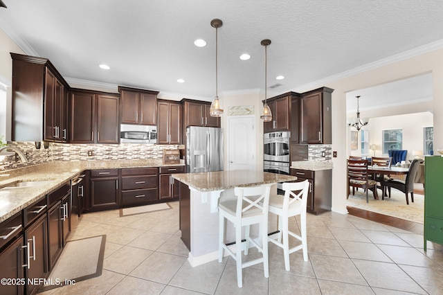 kitchen featuring light tile patterned flooring, sink, a center island, hanging light fixtures, and appliances with stainless steel finishes