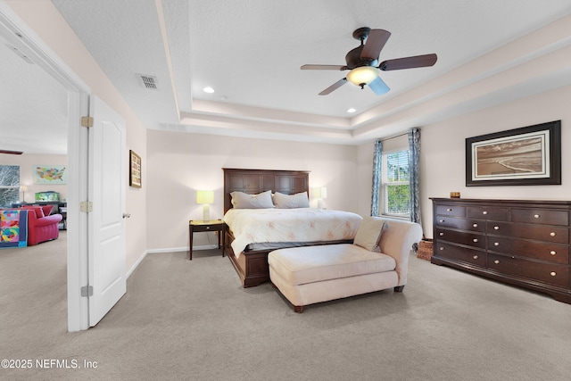 bedroom with ceiling fan, a raised ceiling, and light carpet