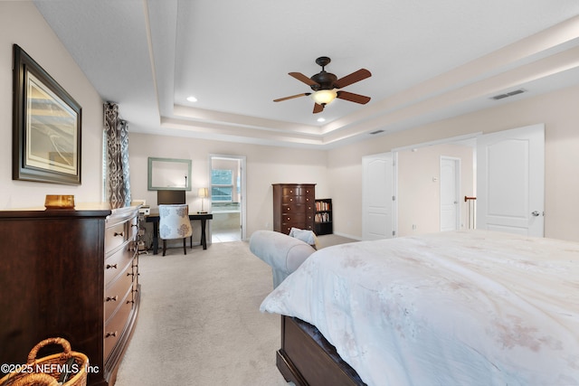 carpeted bedroom with ceiling fan and a tray ceiling