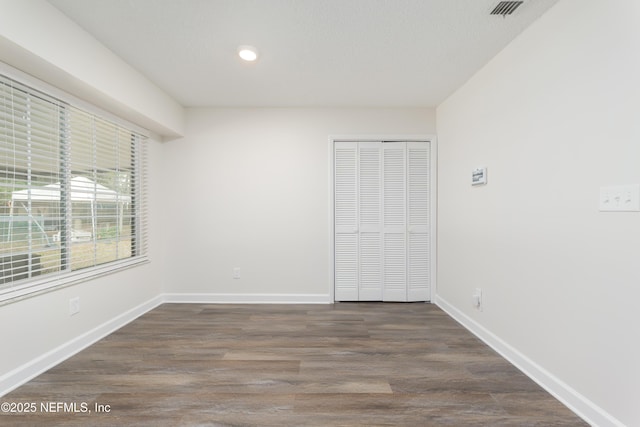 unfurnished bedroom featuring dark wood-type flooring, a textured ceiling, and a closet