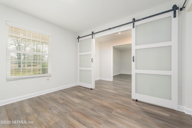 spare room with hardwood / wood-style flooring, a barn door, and a textured ceiling