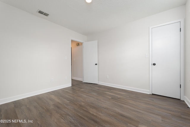 unfurnished room featuring dark hardwood / wood-style floors and a textured ceiling