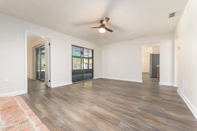 empty room with dark wood-type flooring, a textured ceiling, and ceiling fan