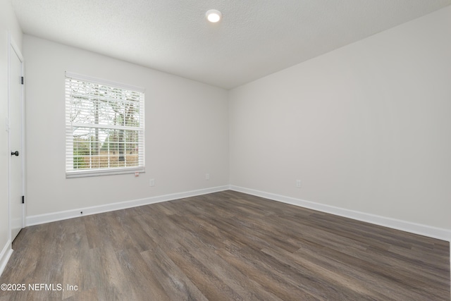 spare room featuring dark hardwood / wood-style flooring and a textured ceiling