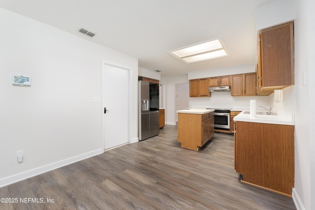 kitchen with appliances with stainless steel finishes, a center island, sink, and dark hardwood / wood-style flooring