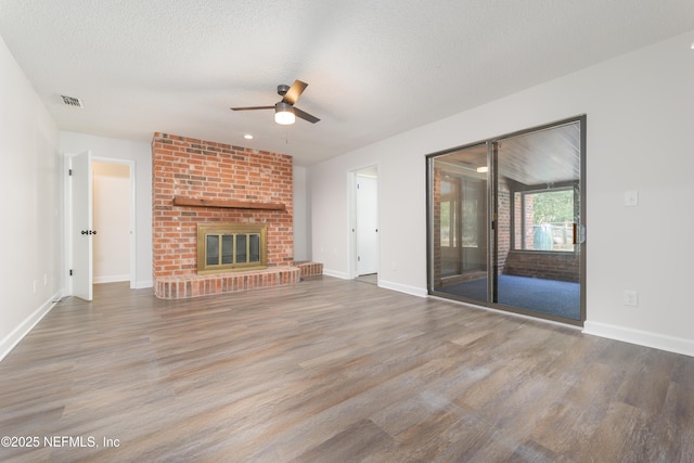 unfurnished living room with ceiling fan, a fireplace, hardwood / wood-style floors, and a textured ceiling