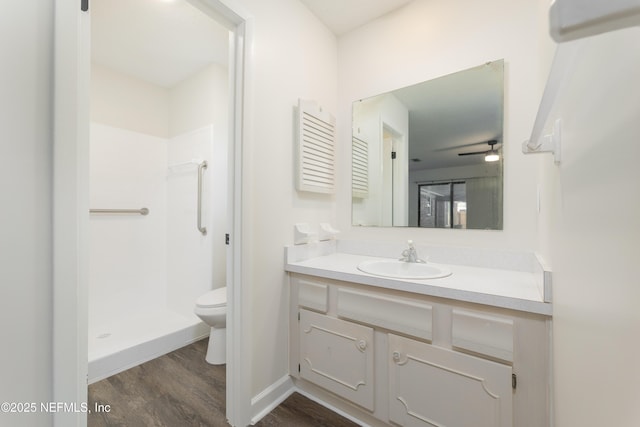 bathroom featuring wood-type flooring, vanity, walk in shower, ceiling fan, and toilet