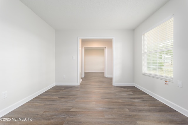 spare room with dark hardwood / wood-style floors and a textured ceiling