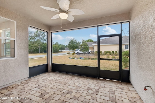 unfurnished sunroom with ceiling fan