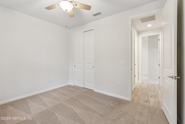 unfurnished bedroom with ceiling fan, a closet, and light carpet