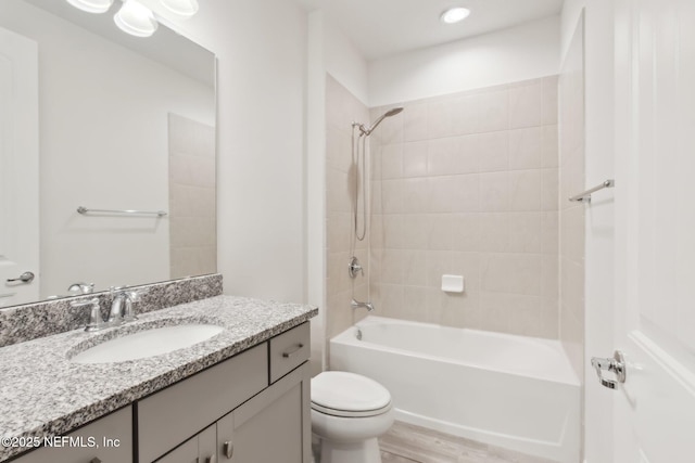 full bathroom with vanity, tiled shower / bath combo, and toilet