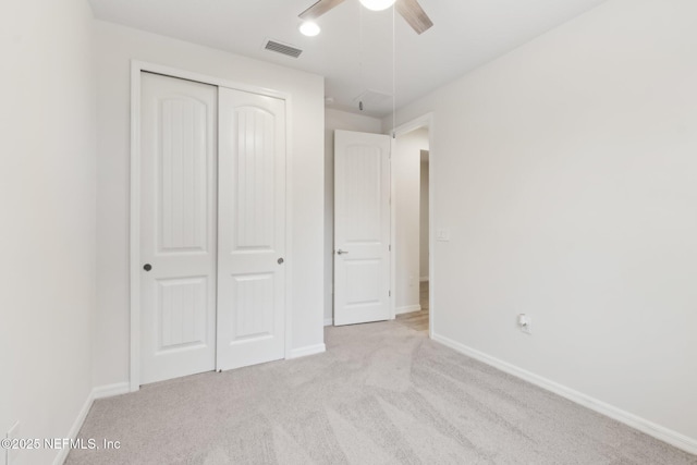 unfurnished bedroom featuring light carpet, ceiling fan, and a closet