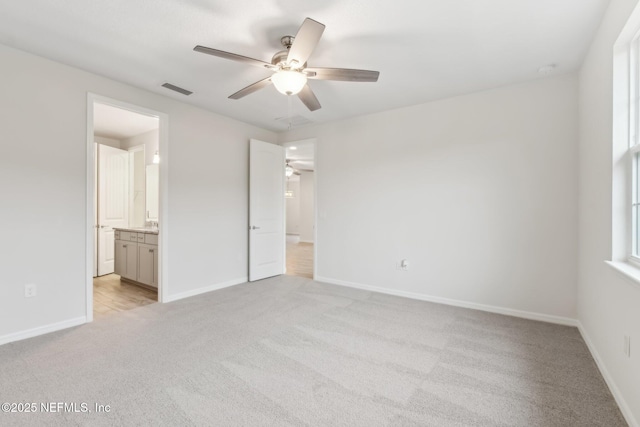 unfurnished bedroom featuring ceiling fan, light colored carpet, and ensuite bathroom