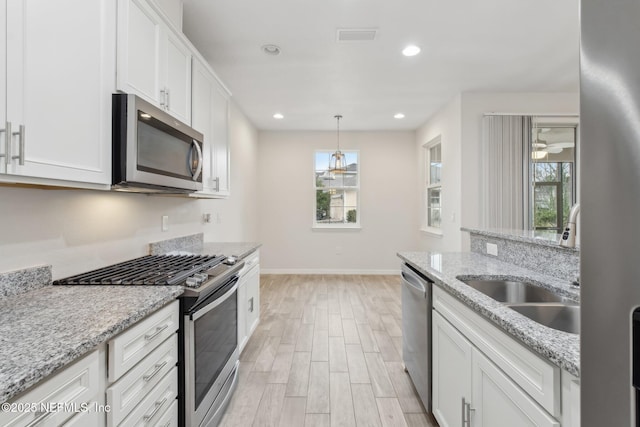 kitchen featuring white cabinetry, hanging light fixtures, light stone countertops, and appliances with stainless steel finishes