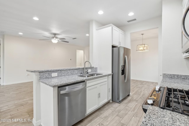 kitchen featuring appliances with stainless steel finishes, white cabinetry, sink, ceiling fan, and light stone counters