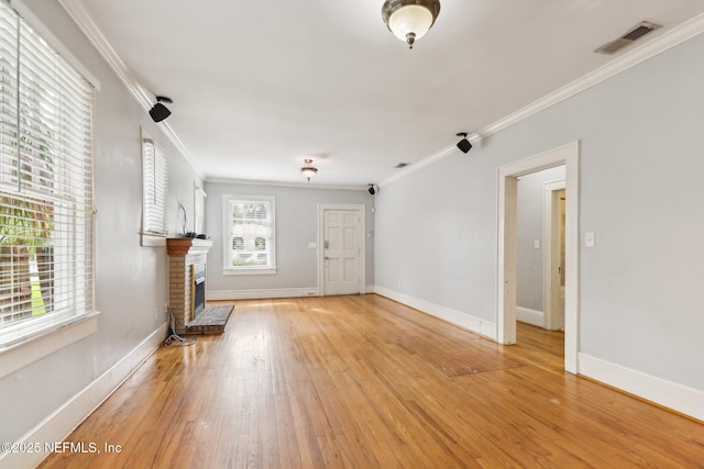 unfurnished living room featuring ornamental molding, a fireplace, and light wood-type flooring