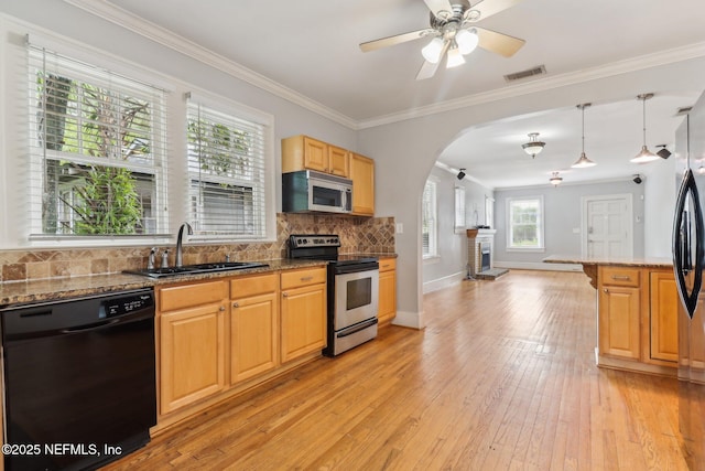 kitchen with sink, crown molding, light wood-type flooring, dark stone counters, and stainless steel appliances