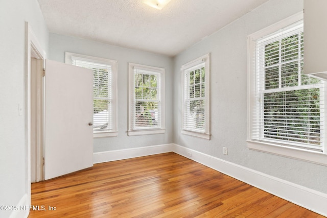 spare room featuring a textured ceiling and light wood-type flooring