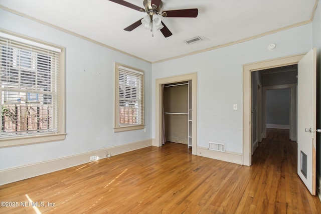 unfurnished bedroom featuring ceiling fan, ornamental molding, hardwood / wood-style floors, and a closet