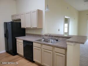 kitchen with sink, decorative light fixtures, kitchen peninsula, light hardwood / wood-style floors, and black appliances