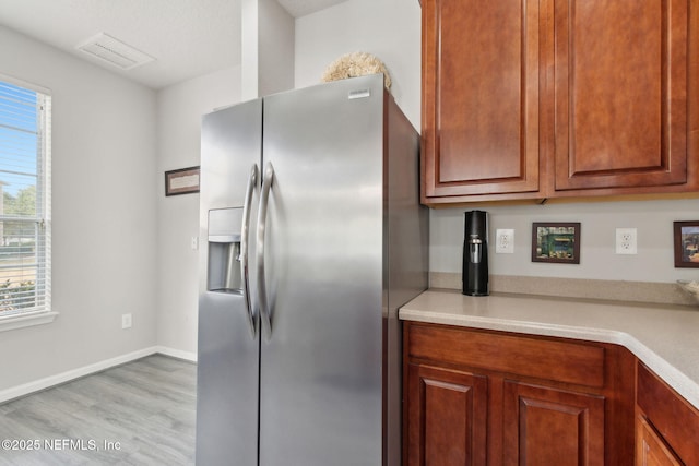 kitchen with stainless steel fridge and light hardwood / wood-style floors