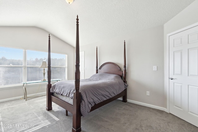 bedroom with light colored carpet, vaulted ceiling, and a textured ceiling