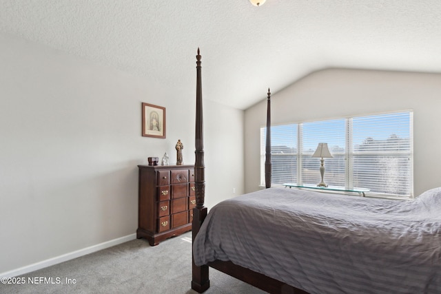 carpeted bedroom with vaulted ceiling and a textured ceiling