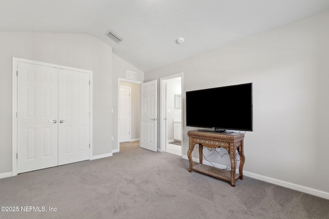 carpeted bedroom featuring ensuite bath, vaulted ceiling, and a closet