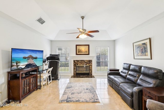 living room featuring a high end fireplace, a wealth of natural light, visible vents, and a tray ceiling