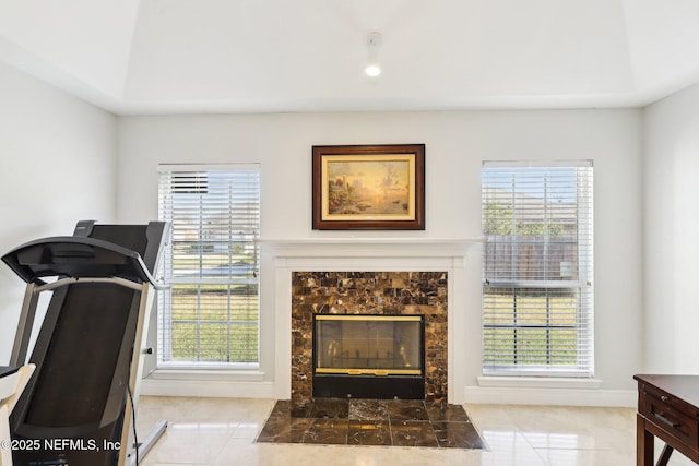 workout room featuring a fireplace and light tile patterned flooring