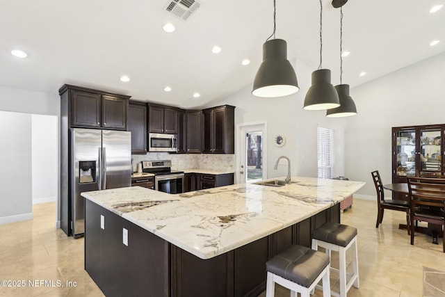 kitchen with a sink, visible vents, appliances with stainless steel finishes, a large island, and decorative light fixtures