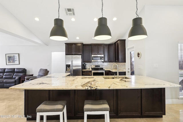 kitchen with a breakfast bar area, a sink, visible vents, appliances with stainless steel finishes, and pendant lighting