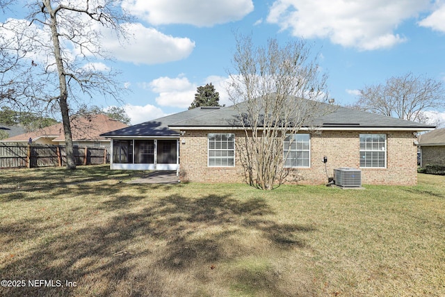 back of house with central air condition unit, brick siding, fence, a sunroom, and a yard