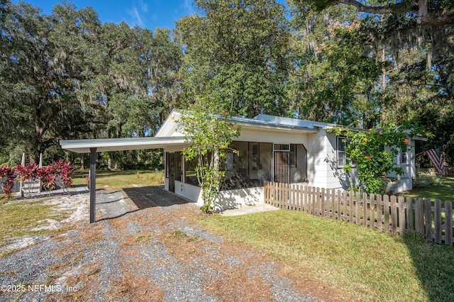 view of front of house featuring a carport, a sunroom, and a front yard