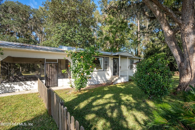 view of front of property featuring a carport, a sunroom, and a front lawn