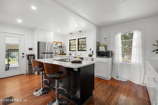 kitchen featuring appliances with stainless steel finishes, a kitchen bar, a center island, and white cabinets