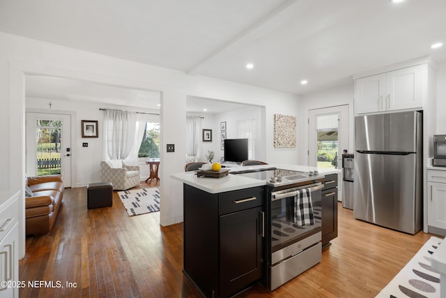 kitchen featuring white cabinetry, appliances with stainless steel finishes, a center island, and light wood-type flooring