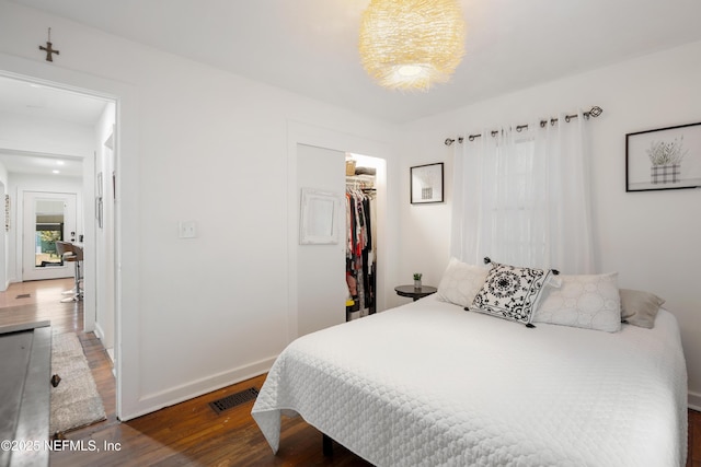 bedroom with a walk in closet, dark hardwood / wood-style floors, and a closet