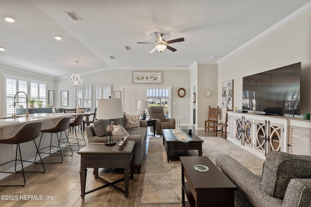 living room featuring ornamental molding, vaulted ceiling, ceiling fan, and light hardwood / wood-style flooring