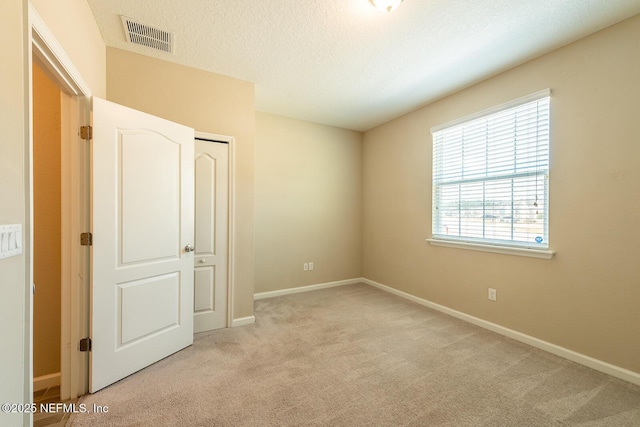 unfurnished bedroom featuring light colored carpet and a textured ceiling